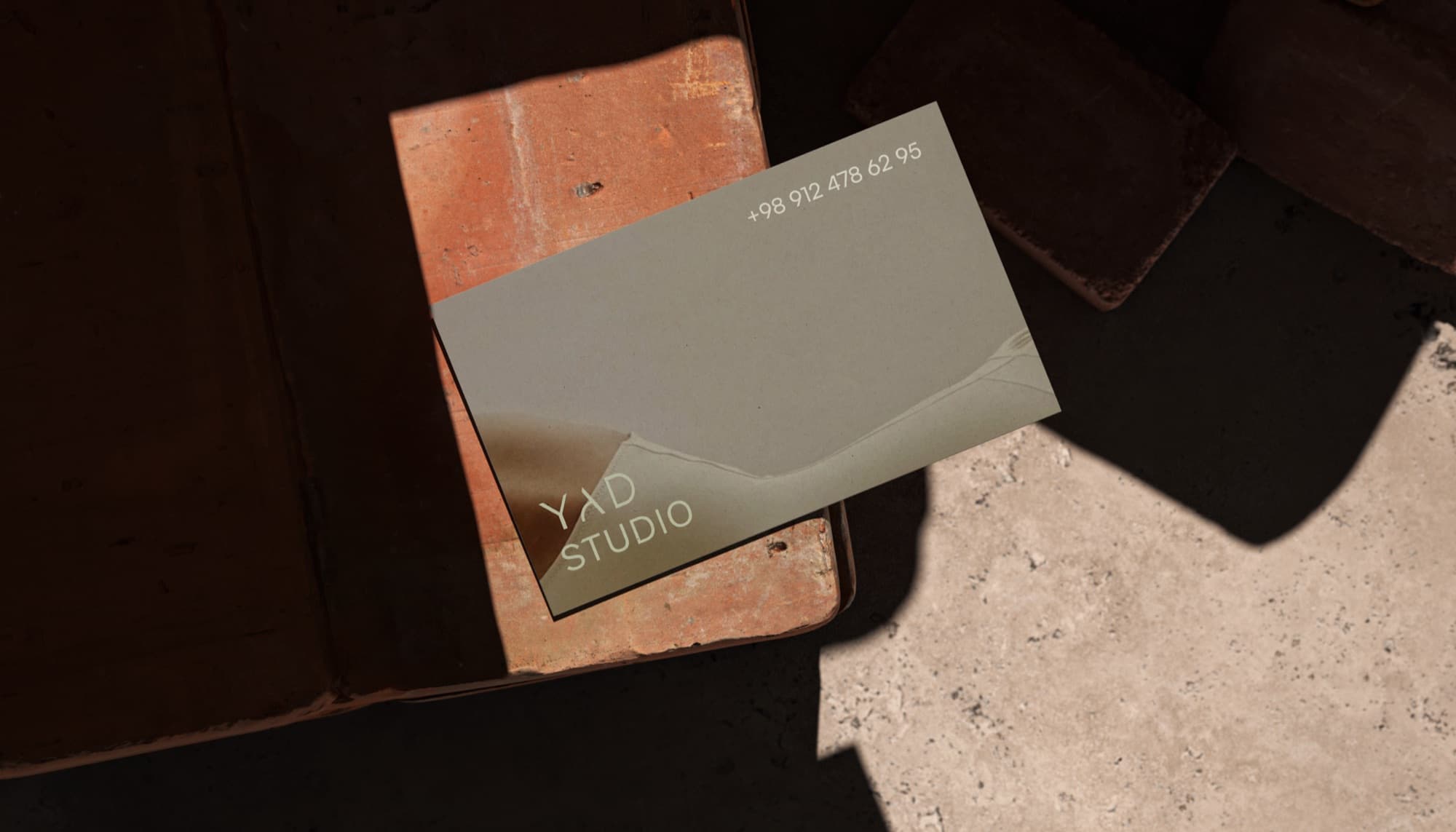 YAD Studio business card resting on a textured surface.