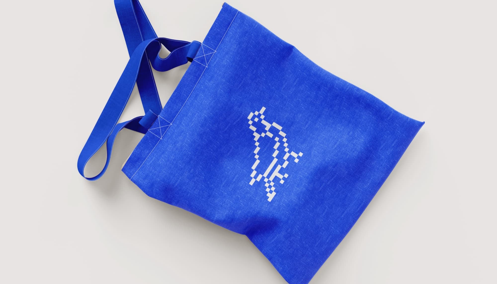 Electric-blue linen tote bag carrying the pixel-pigeon mark.