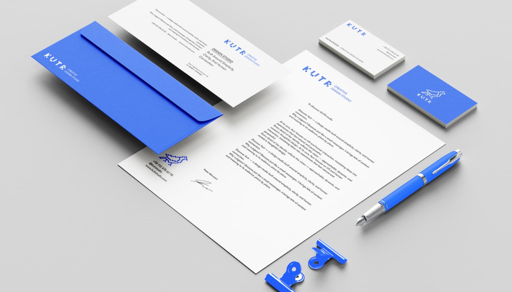 KUTR print collateral flatlay with envelope, letterhead, cards and pen.